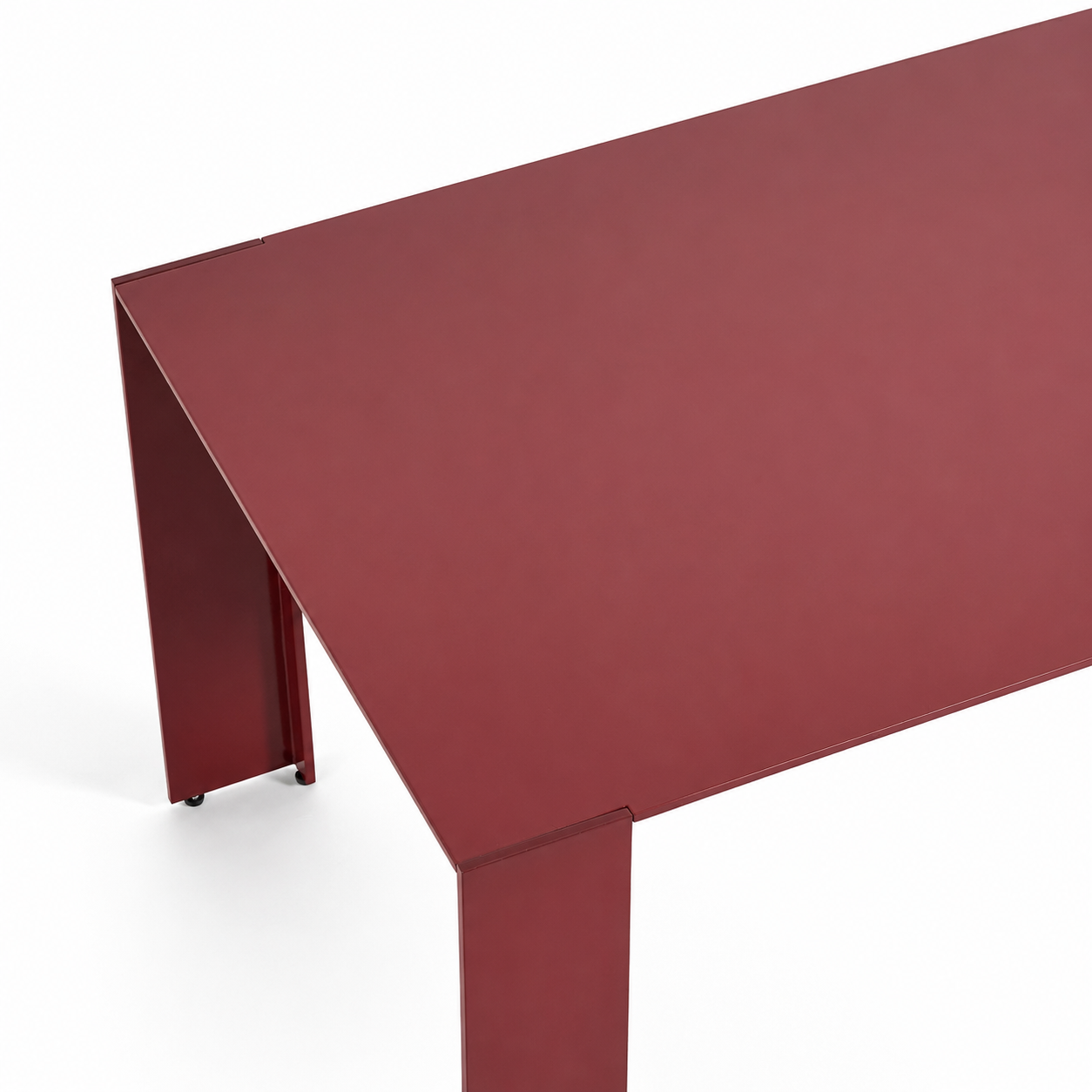 A close-up studio shot of a modern table corner with a matte dark red top and matching leg on a white background.