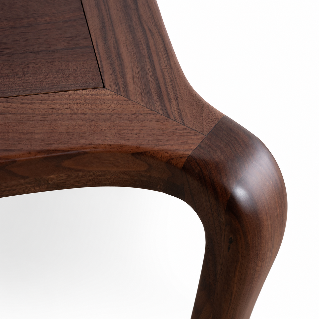 Close-up of a dark American Walnut table showing the corner joint and curved leg against a white background.