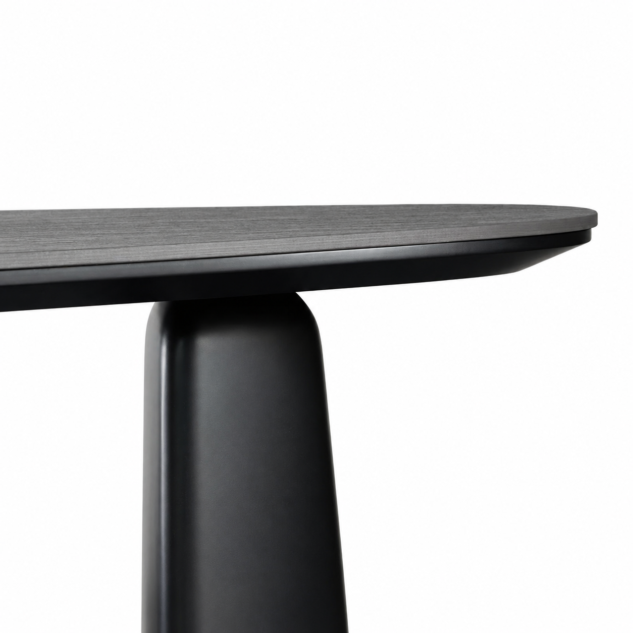 Close-up of the Oris table showing a dark wood grain tabletop edge and a matte black tapered pedestal leg against a white background.