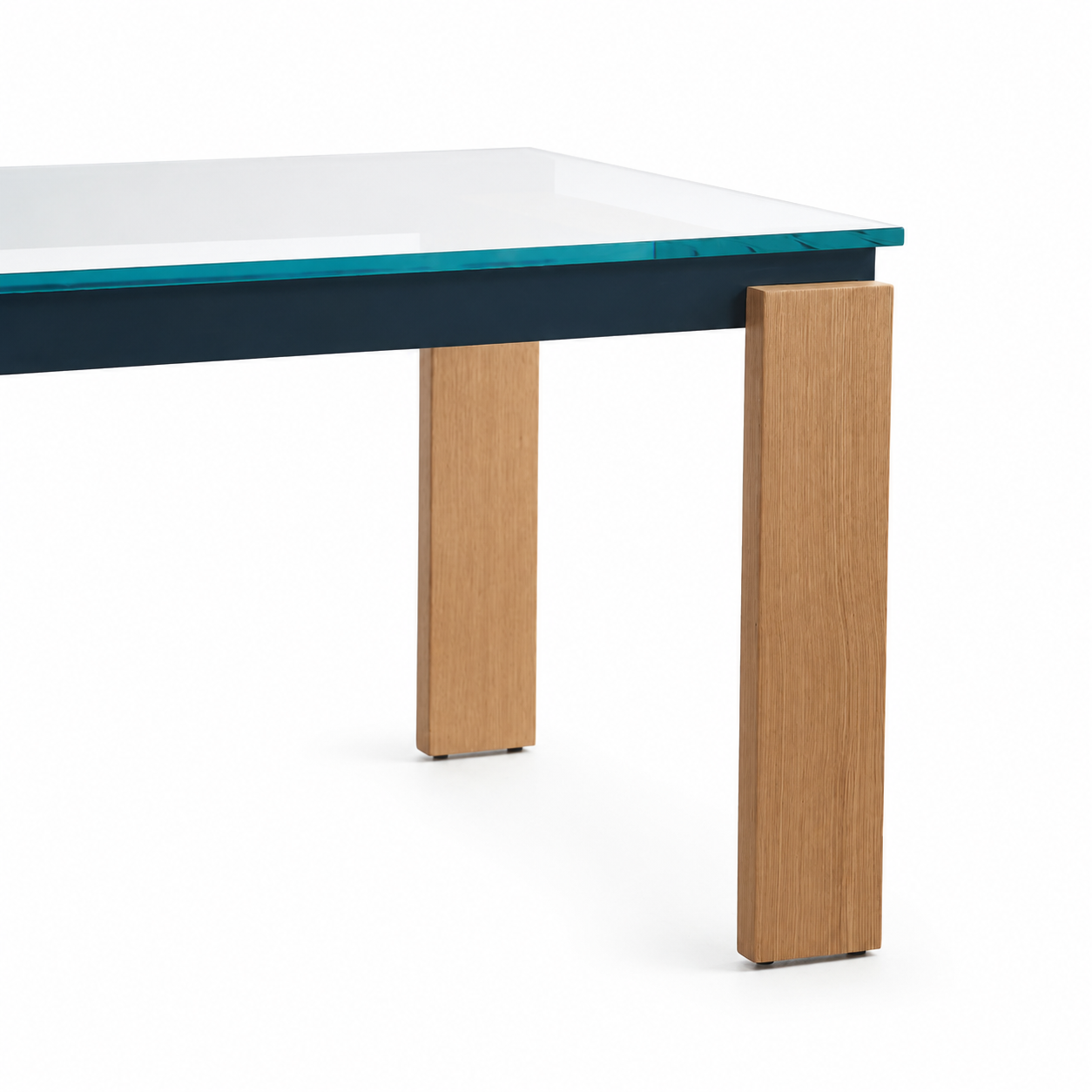 Modern dining table featuring a clear glass top, a dark navy blue apron, and thick rectangular light oak legs, shown on a white background.
